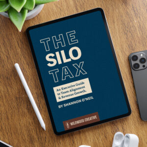 An ipad sits on a desktop showing the cover image for The Silo Tax, an executive guide to sales team alignment.