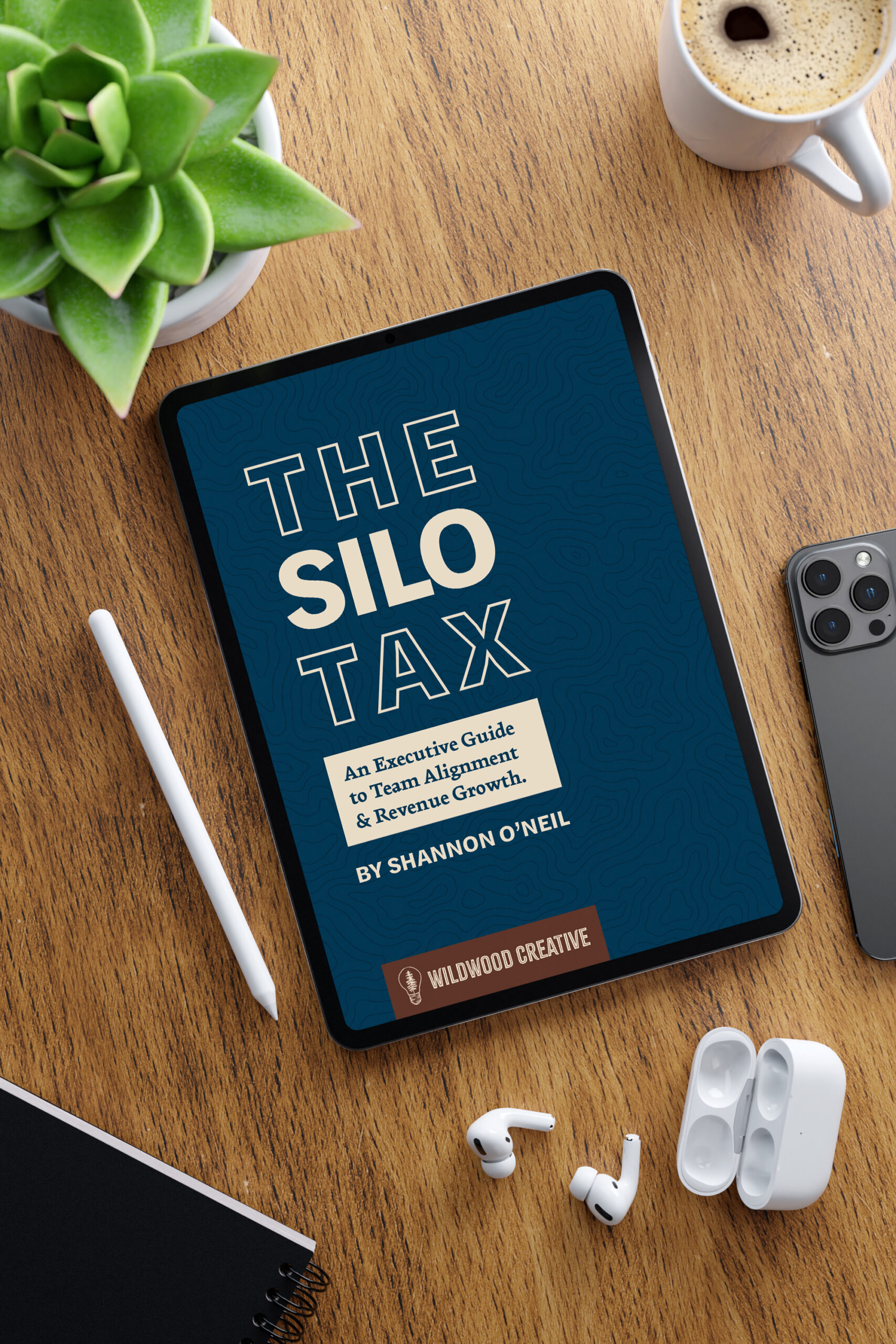 An ipad sits on a desktop showing the cover image for The Silo Tax, an executive guide to sales team alignment.